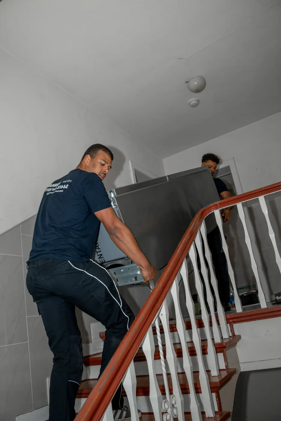 Zwei Mitarbeiter von Maassen Umzüge tragen ein schweres Möbelstück die Treppe hoch in Krefeld