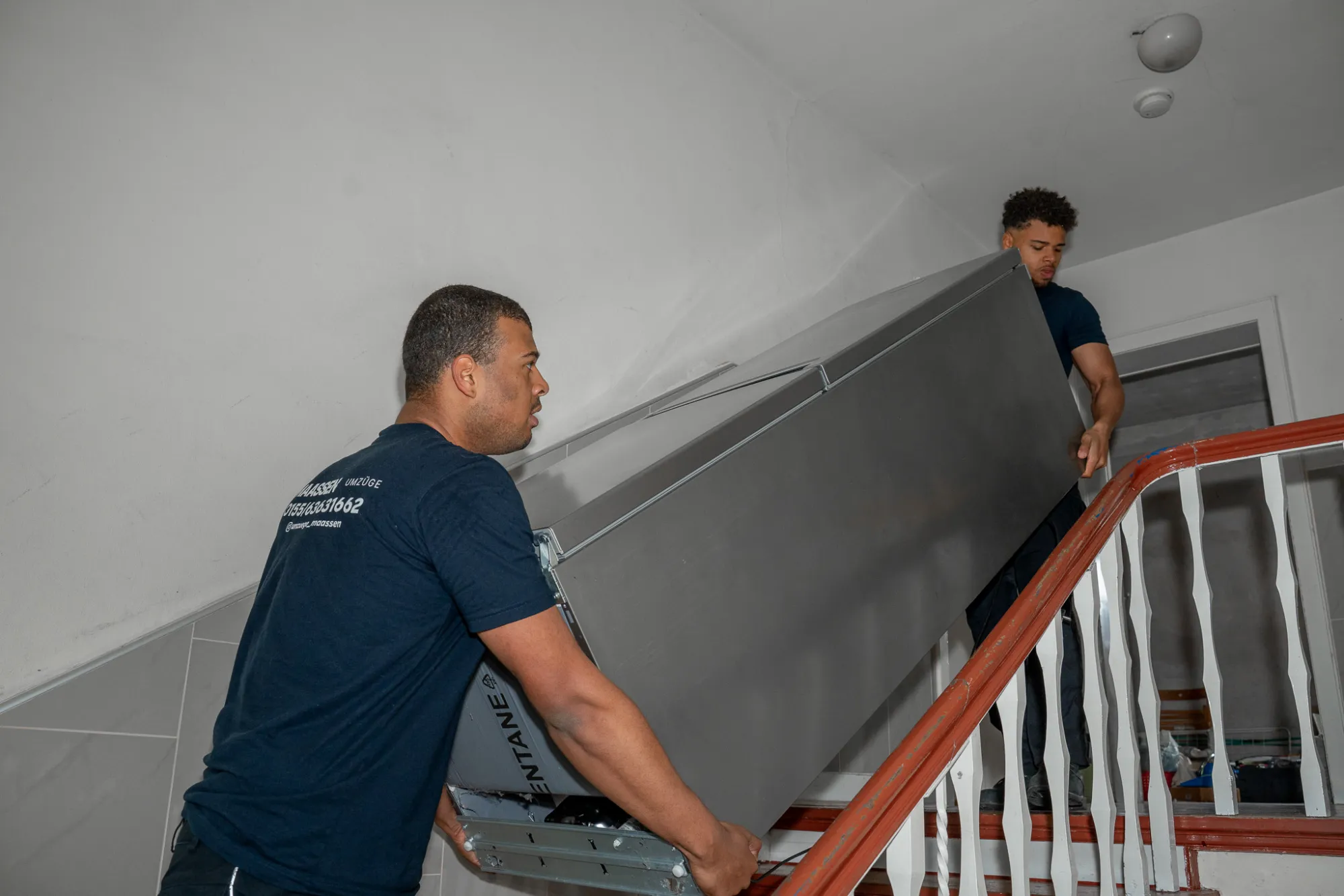 Möbelmontage Krefeld – Maassen Umzüge transportiert ein großes Möbelstück über die Treppe