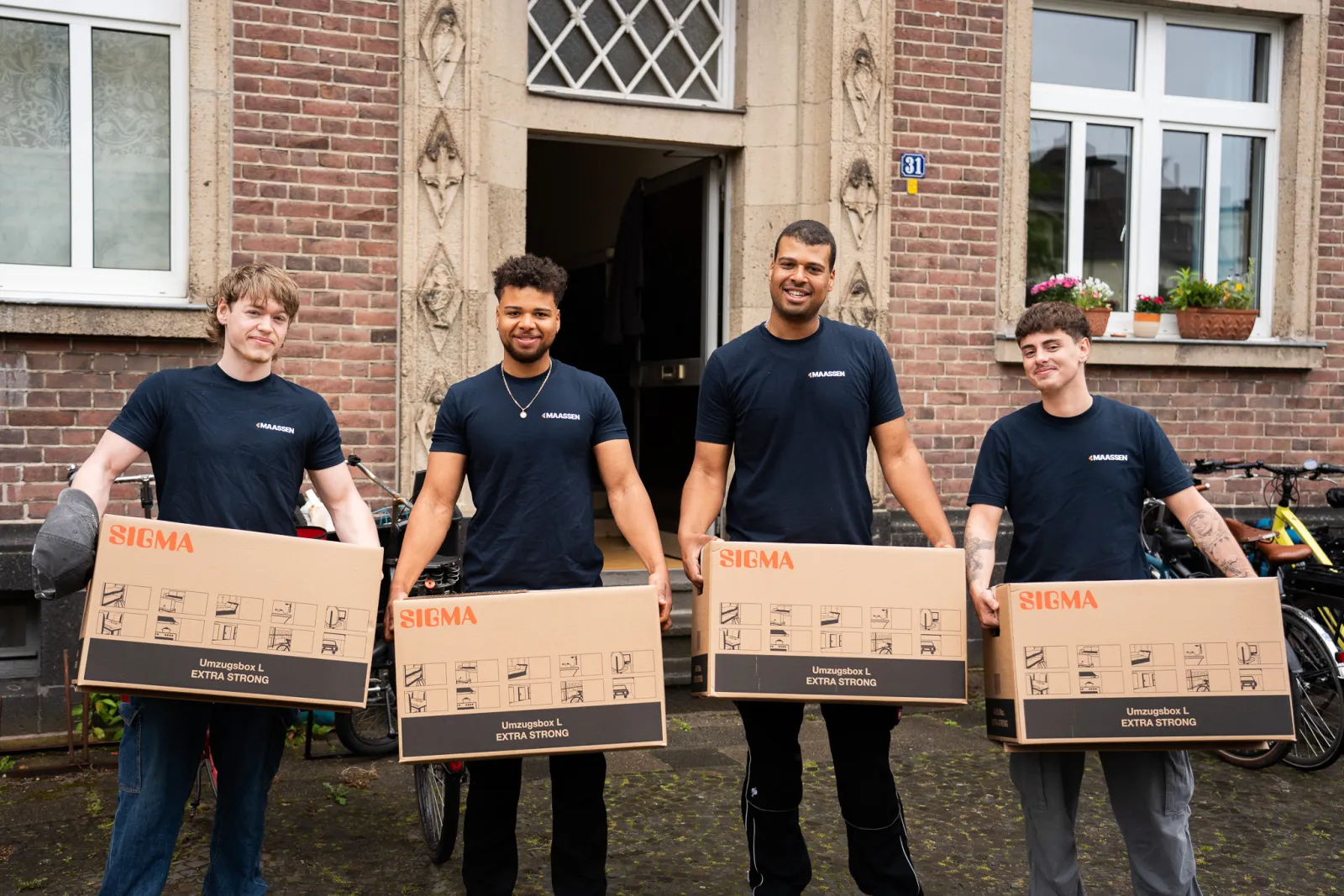 Das Team von Maassen Umzüge mit Umzugskartons vor einem Haus in Krefeld